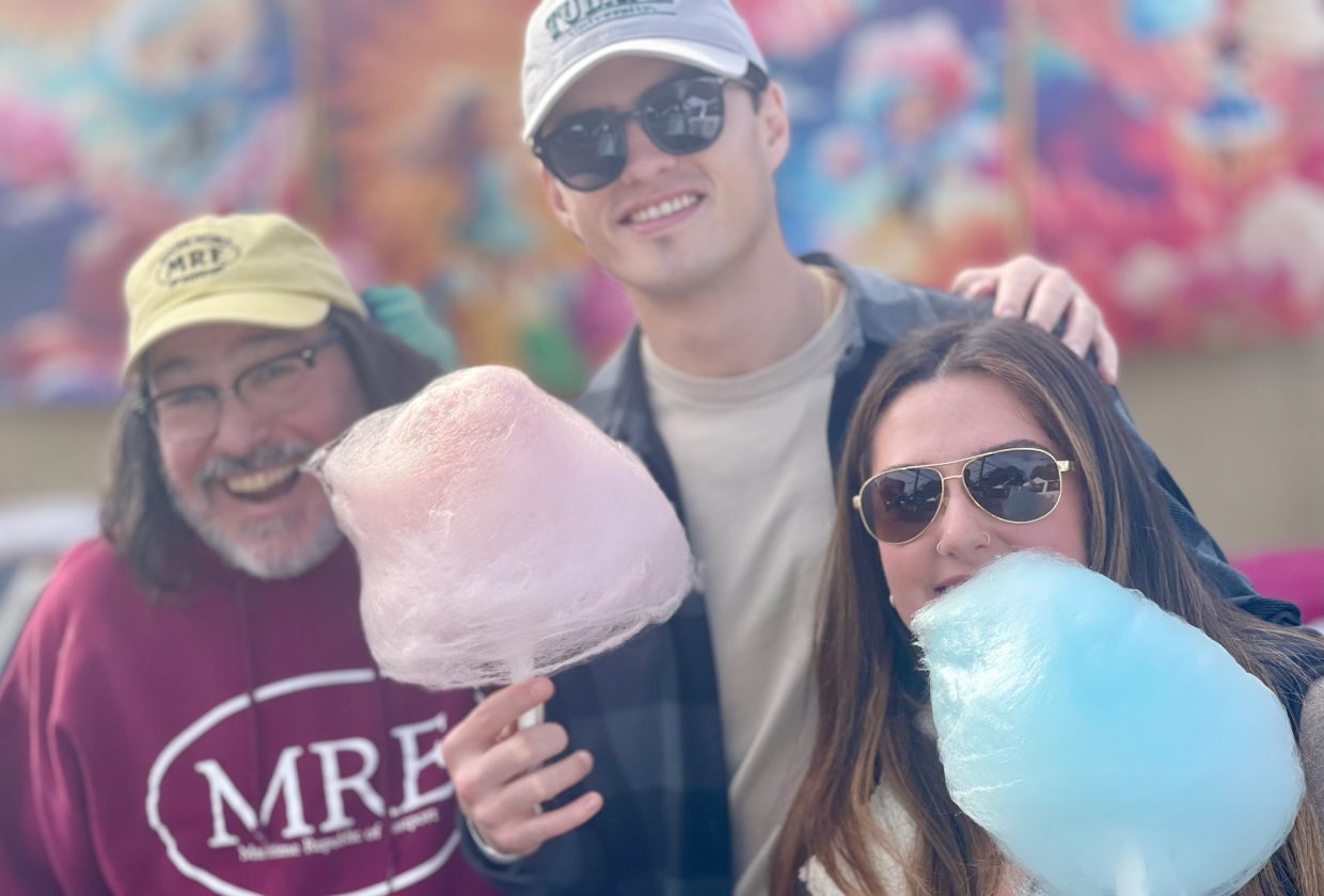 Three adults enjoying cotton candy.